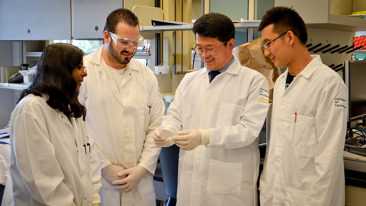 A team of students discuss their research with a professor in the lab